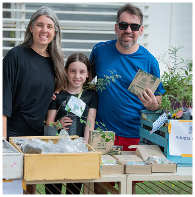 Una familia en una feria de Mundo Huertas con plantines y cajas de semillas
